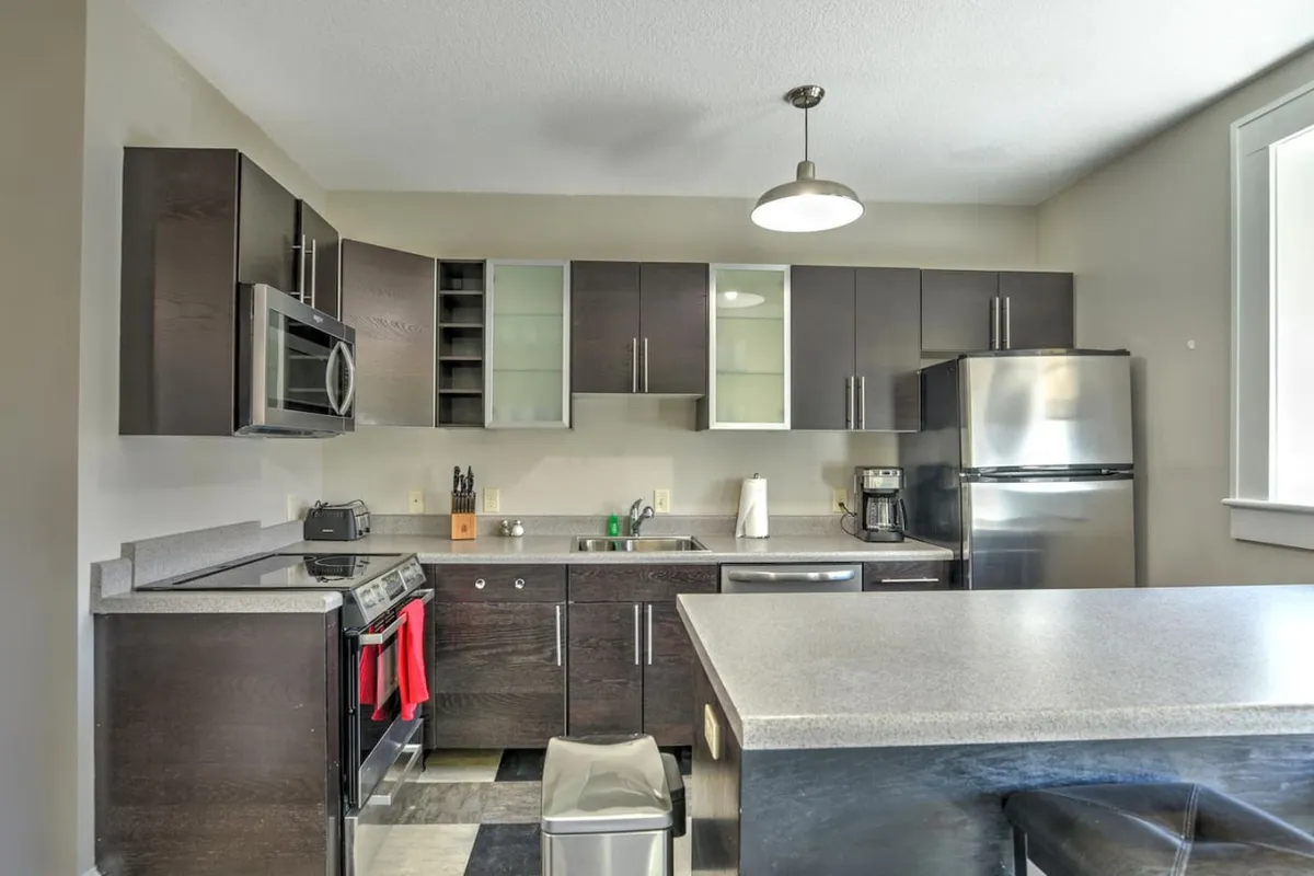 A modern kitchen island anchors the renovated dining area, featuring stainless steel appliances and rich cabinetry. The space is functional and stylish, seamlessly integrated within the open floor plan for easy hosting and shared meals.